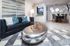 Modern living room with chic black sofa, geometric cushions, and a sleek silver coffee table. Open kitchen and elegant dining area with stylish decor complete the contemporary look.