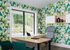 Modern office space with vibrant geometric wall design, large window view, wooden desk, and stylish chairs.