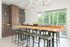 Contemporary kitchen with stylish wooden countertop, sleek pendant lighting, and lush views through expansive windows.