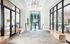 Elegant apartment lobby showcasing modern glass doors, chic lighting fixtures, and a view of a serene outdoor pool area.