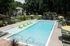 Luxurious apartment pool area featuring modern green loungers, poolside cabanas, and lush greenery for a relaxing escape.