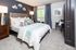 Inviting bedroom with elegant decor featuring a plush bed, stylish cushions, and contemporary art; brightened by natural light from large windows and complemented by modern lighting fixtures.