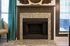 Charming living space with a beautifully designed granite fireplace, surrounded by elegant decor and serene teal curtains.