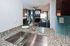 Modern kitchen view with sleek granite countertops, stainless steel sink, and bright living room in the background featuring elegant decor and natural lighting.