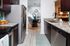Modern kitchen with sleek stainless steel appliances and elegant granite countertops, leading to a stylishly decorated dining area with unique wall art.