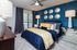 Modern bedroom with stylish blue and yellow decor, featuring elegant wall accents, luxurious bedding, and mirrored furniture.