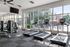 Modern fitness center with state-of-the-art equipment and bright, spacious interior overlooking a serene outdoor pool area.