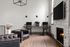 Charming living area with sleek workspace, cozy fireplace, and elegant leather armchairs on polished wooden floors.