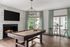 Chic entertainment room featuring a modern pool table, cozy fireplace, and elegant seating under natural light.