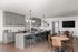 Chic open-concept kitchen and dining area with sleek gray cabinetry, elegant pendant lighting, and stylish seating arrangements.