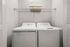 Modern in-unit laundry room with sleek washer and dryer, featuring ample shelving for storage convenience.