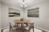 Charming dining area featuring a round wooden table with modern chairs, highlighted by elegant paintings and a chic ceiling light, creating a cozy ambiance.