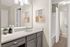Modern bathroom with sleek gray cabinetry, elegant countertop, and stylish artwork, featuring chic lighting and a fresh, inviting atmosphere.