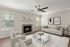 Inviting living room with cozy fireplace, stylish ceiling fan, and elegant neutral decor.