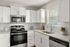 Modern kitchen with sleek white cabinetry, stainless steel appliances, and a sunlit window for a bright and inviting cooking space.