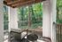 Tranquil balcony retreat with modern seating, nestled amid lush green trees, perfect for relaxation.