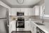 Modern kitchen with sleek stainless steel appliances, pristine white cabinetry, and ample natural light.