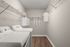 Modern laundry room with pristine appliances, elegant shelving for storage, and a stylish wooden floor, perfect for efficient home management.