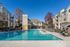 Luxurious apartment complex with pristine swimming pool, surrounded by modern buildings and serene outdoor seating.