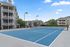Charming apartment complex showcasing modern architecture with a pristine tennis court under a clear blue sky.