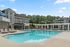 Luxurious apartment complex featuring a sparkling pool, elegant lounge chairs, and stylish architecture set amidst lush greenery.