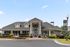 Charming residential building with modern architecture, featuring a welcoming entrance surrounded by vibrant landscaping and clear blue skies.