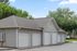 Charming residential garage units with classic white doors, nestled in a peaceful, tree-lined neighborhood.