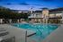 Elegant apartment complex with a spacious pool area, surrounded by inviting lounge chairs and illuminated by soft evening lights, perfect for relaxation.