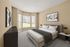 Inviting bedroom with plush carpeting, large bay windows, and modern art, offering serene views and abundant natural light.