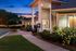 Charming leasing office exterior surrounded by lush landscaping and vibrant floral accents, set against a serene twilight sky.