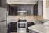Modern kitchen with sleek dark wood cabinetry, stainless steel appliances, and elegant stone countertop.