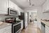 Modern kitchen with sleek stainless steel appliances, granite countertops, and bright open layout leading to a cozy living area.