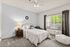Charming bedroom with elegant decor, featuring a plush bed, cozy armchair, ambient lighting, and a large window inviting natural light.