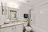 Bright and modern bathroom with elegant granite countertops, large mirror, and clean white finishes, offering a serene atmosphere.