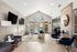 Luxurious and modern apartment lounge featuring sleek furnishings, dual flat-screen TVs, and a captivating fireplace, with a view of a sparkling pool through large windows.