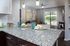 Contemporary apartment with elegant granite countertop, stylish dining setup, and cozy living area featuring chic decor and large windows offering garden views.