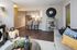 Inviting open-plan living area featuring a cozy couch, elegant decor, modern kitchen with stainless steel appliances, and stylish bar seating.