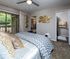 Elegant bedroom with chevron-patterned bedding, stylish wall decor, and access to scenic balcony views, leading to a modern bathroom and cozy living area.