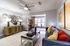 Contemporary living room with chic decor, featuring a plush sofa with colorful cushions, elegant art pieces, and a stylish ceiling fan.
