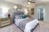 Elegant bedroom featuring a plush gray headboard, artistic wall decor, and stylish mirrored nightstands with ambient lighting.