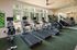 Bright, modern fitness center equipped with state-of-the-art treadmills and elliptical trainers, featuring large windows and lush outdoor views.