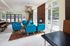 Modern living area with vibrant blue seating, stylish wooden accents, and a cozy fireplace, overlooking a scenic patio.