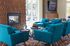 Chic apartment lounge featuring vibrant teal armchairs, a cozy fireplace, and modern decor, ideal for relaxation and social gatherings.