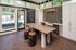 Modern and elegant kitchen with sleek countertops, unique barrel-style stools, wine storage, and large windows offering a bright and airy feel.