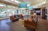 Inviting modern living room with large windows, stylish wood furniture, colorful cushions, and chic lighting, overlooking a serene outdoor pool area.