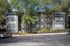 Charming apartment building surrounded by lush greenery and ample parking space, perfect for modern living.