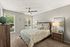 Cozy bedroom with elegant decor, featuring a plush bed with patterned bedding, stylish nightstands, and large windows offering natural light.