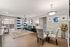 Bright and modern open-concept living room with stylish decor, featuring a comfortable blue sectional, elegant glass dining table, and chic blue-striped curtains, perfect for contemporary living.