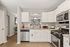Bright and modern kitchen featuring sleek white cabinets, granite countertops, and stainless steel appliances with an inviting open view to the dining area.