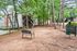 Charming community view with inviting outdoor seating amidst lush trees and modern apartment buildings, perfect for relaxation and nature lovers.